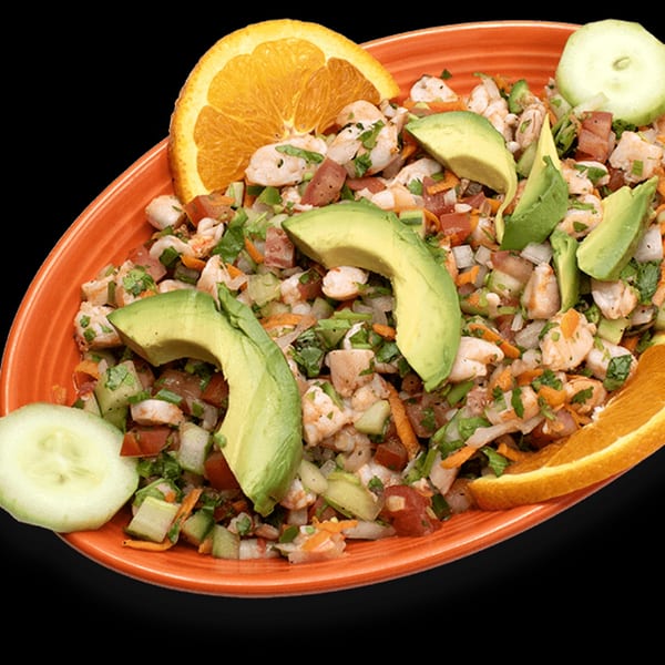 Almanza's shrimp ceviche with avocado, cucumber, and orange slices in an orange dish.